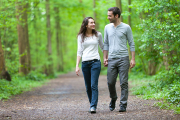 Young couple having a walk in a forest - obrazy, fototapety, plakaty