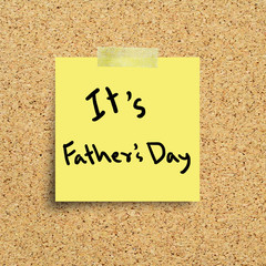 Sticky note with Happy Fathers Day on a cork bulletin board.