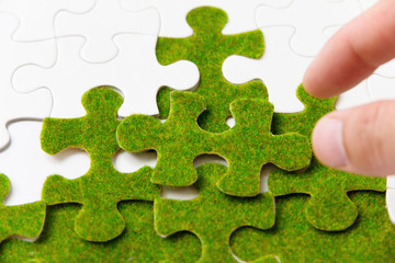hand holding a green puzzle piece, green concept
