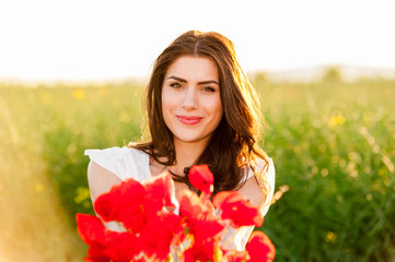 Naklejka premium Beautiful woman over Sky and Sunset holding poppies