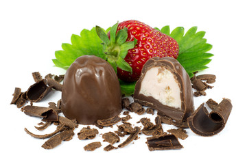 Chocolate candies and strawberry on green leaf isolated on white