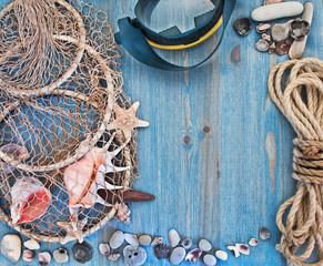 Diver mask and mesh with shells on blue wooden background