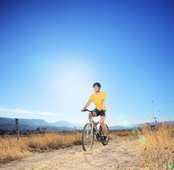 Fototapeta na wymiar Young biker riding mountain bike in a field