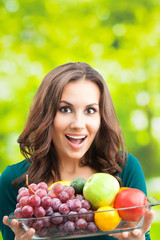 Woman with plate of fruits, outdoors