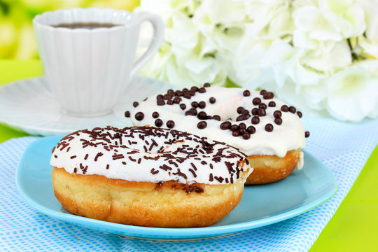 Sweet donuts with cup of tea on table close-up