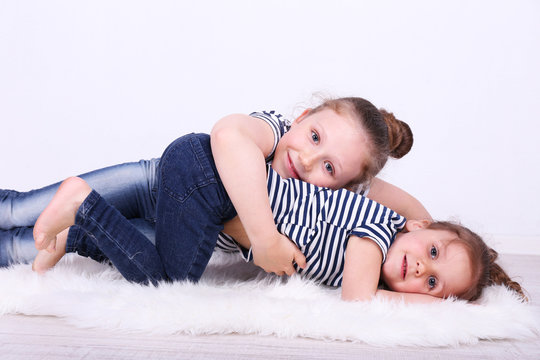 Beautiful small girls lying on floor on wall background