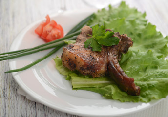 pork steak on lettuce with tomatoes and onions
