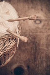 Natural woolen yarn and knitting on vintage wooden background
