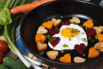 Fried potatoes, carrots, beets and egg in a heart shape