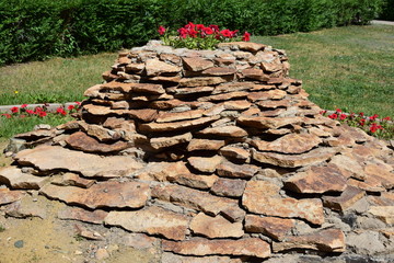 Flowerbed shaped as a small hill of schist stones