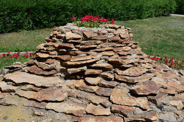 Flowerbed shaped as a small hill of schist stones