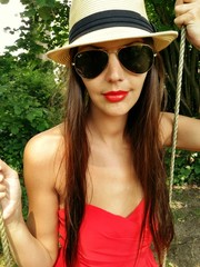 Portrait of woman wearing red dress, on a swing