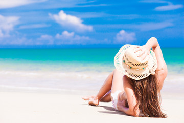 long haired woman in bikini and straw hat at tropical beach