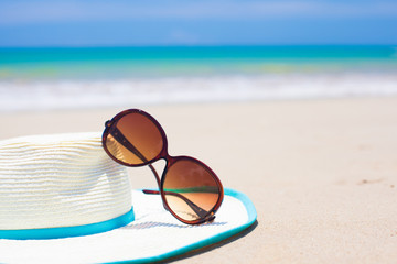 Fototapeta na wymiar sunglasses and straw hat on tropical beach