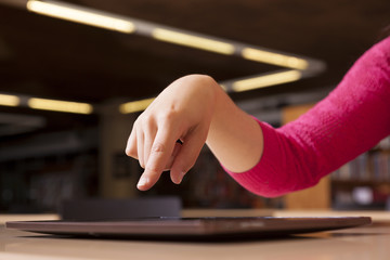 Hand pointing to tablet computer in library