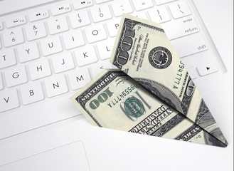Paper plane from dollar bills lying on keyboard