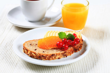 Bread with butter, cup of tea and orange juice