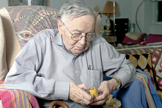 Senior Man Sitting On Couch Eating Banana