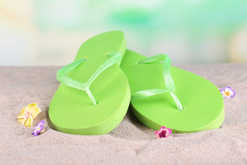 Bright flip-flops on sand, on nature background