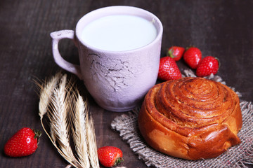 Ripe sweet strawberries in wooden bowl and mug with milk