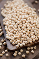 Close-up of raw chickpeas over wooden background, studio shot
