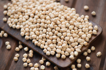Rustic wooden cutting board with raw chickpeas, close-up
