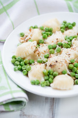 Plate with cheese ravioli served with green peas and walnuts