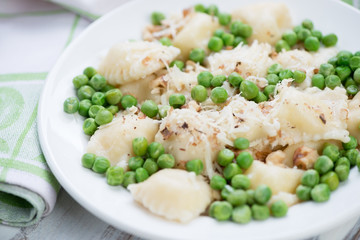 Close-up of ravioli with green peas, nuts and parmesan