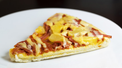 slice of fresh baked pizza hawiian on white dish