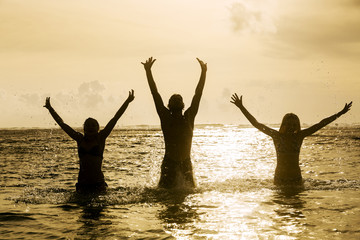 Silhouettes of people jumping in ocean