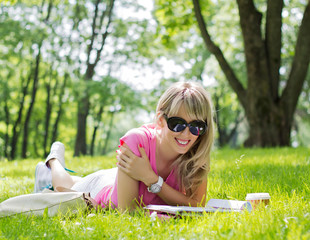Happy young woman reading magazine in park