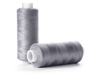 Two reels of gray thread on white background
