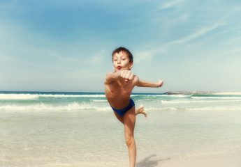 Fototapeta na wymiar Beautiful child running on the beach with funny expression