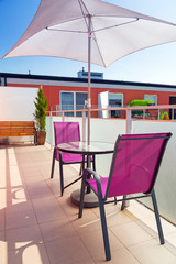 Table with sun parasol on the apartment balcony