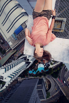 Young girl lying on the edge of a skyscraper
