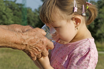 hands of the grandmother and water for the grandaughter