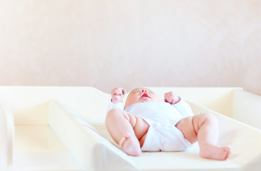 cute infant baby on changing table © Olesia Bilkei