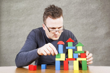 Man builds the house of children's toy blocks