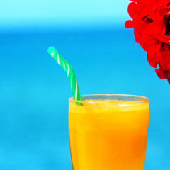 Close up of a orange juice by the sea.