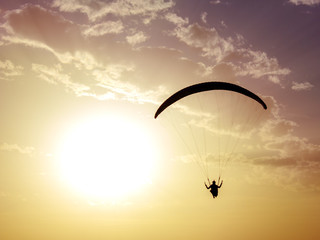 Silhouette of paragliding with sunset background.