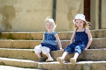 Two cute little sisters sitting on stairs © MNStudio
