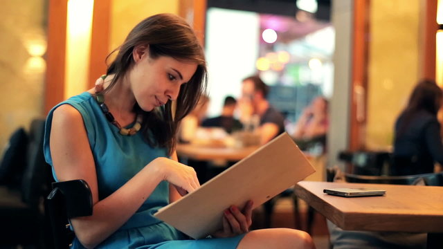 Young woman reading menu in restaurant