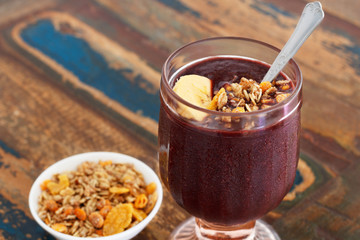 Acai in glass with muesli banana on wooden table