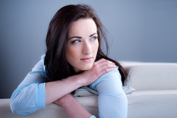 Naklejka premium cheerful young brunette lying on her sofa relaxed at home