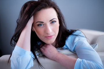 cheerful young brunette lying on her sofa relaxed at home