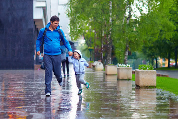 happy father and son running under the rain