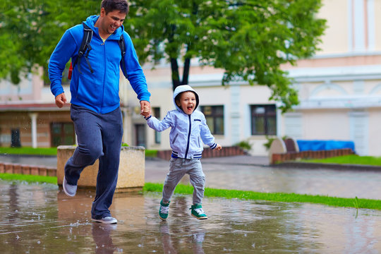 Happy Father And Son Running Under The Rain