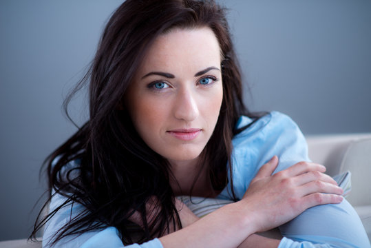 cheerful young brunette lying on her sofa relaxed at home