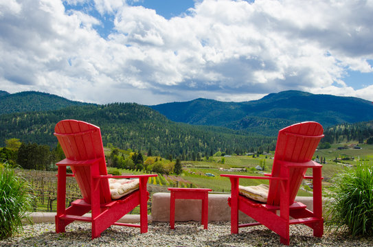 Two empty red chairs overlooking vineyards
