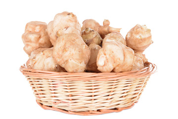 Topinambur roots in wicker basket isolated on white